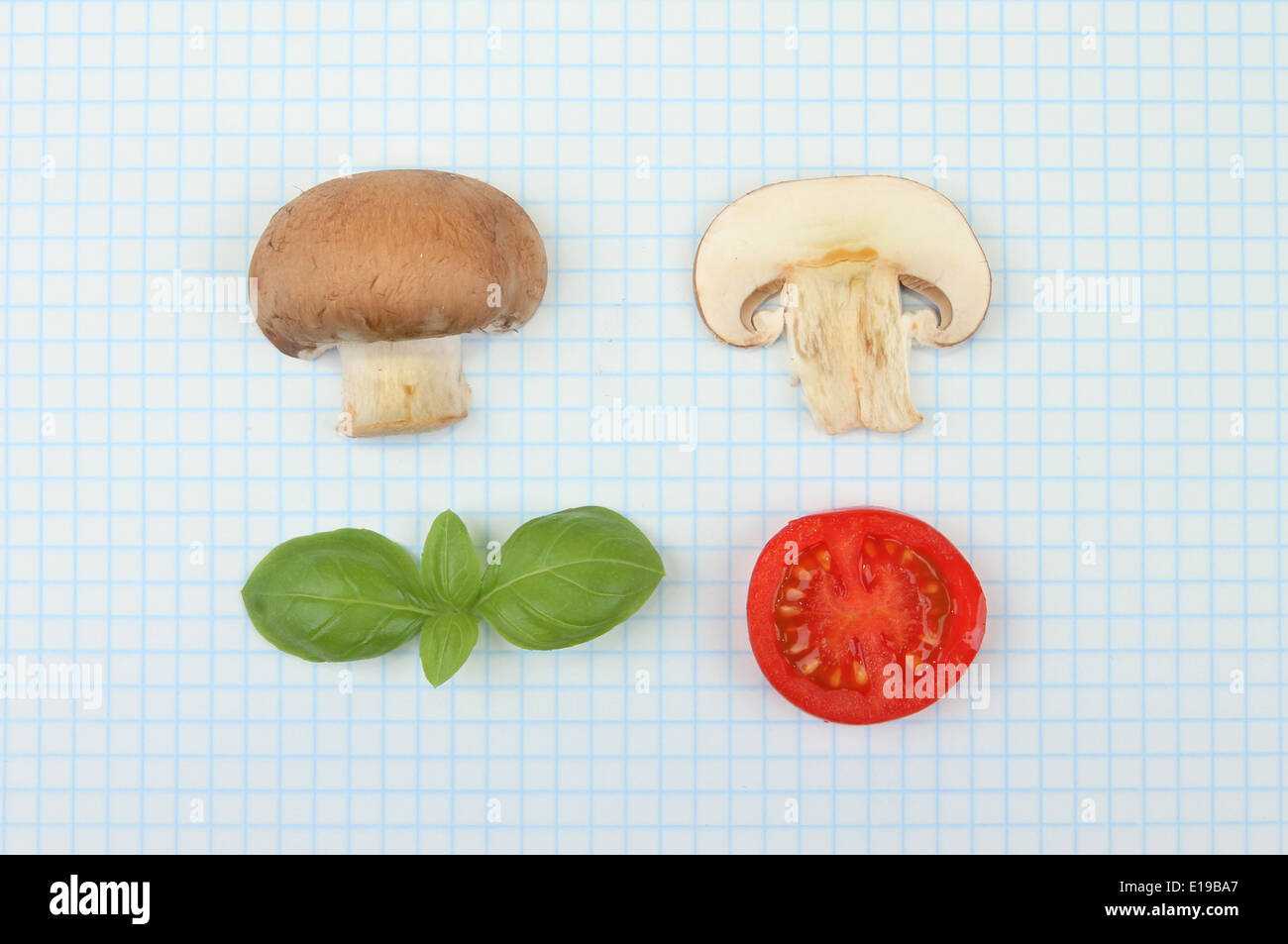 Scienza alimentare concetto, funghi, basilico e pomodoro su un foglio di carta millimetrata Foto Stock