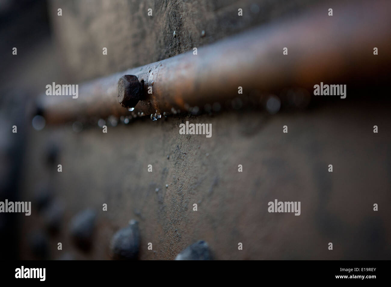 Gocce d'acqua pendente da una vecchia vite di ruggine, la profondità di campo di una immagine. Foto Stock