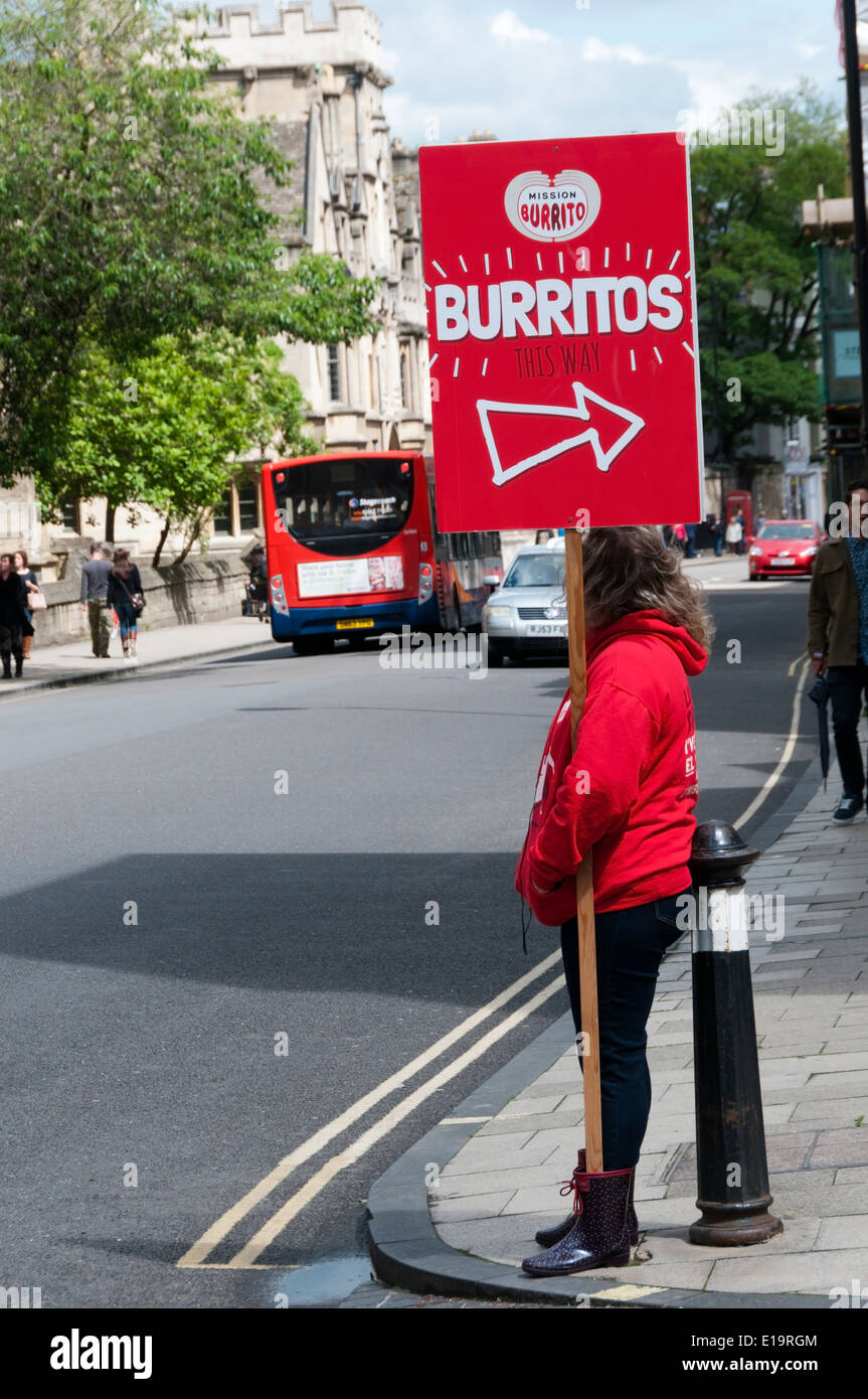 Donna che mantiene un bordo missione pubblicità Burrito in Oxford. Foto Stock Donna che mantiene un bordo missione pubblicità Burrito in Oxford. Foto Stock