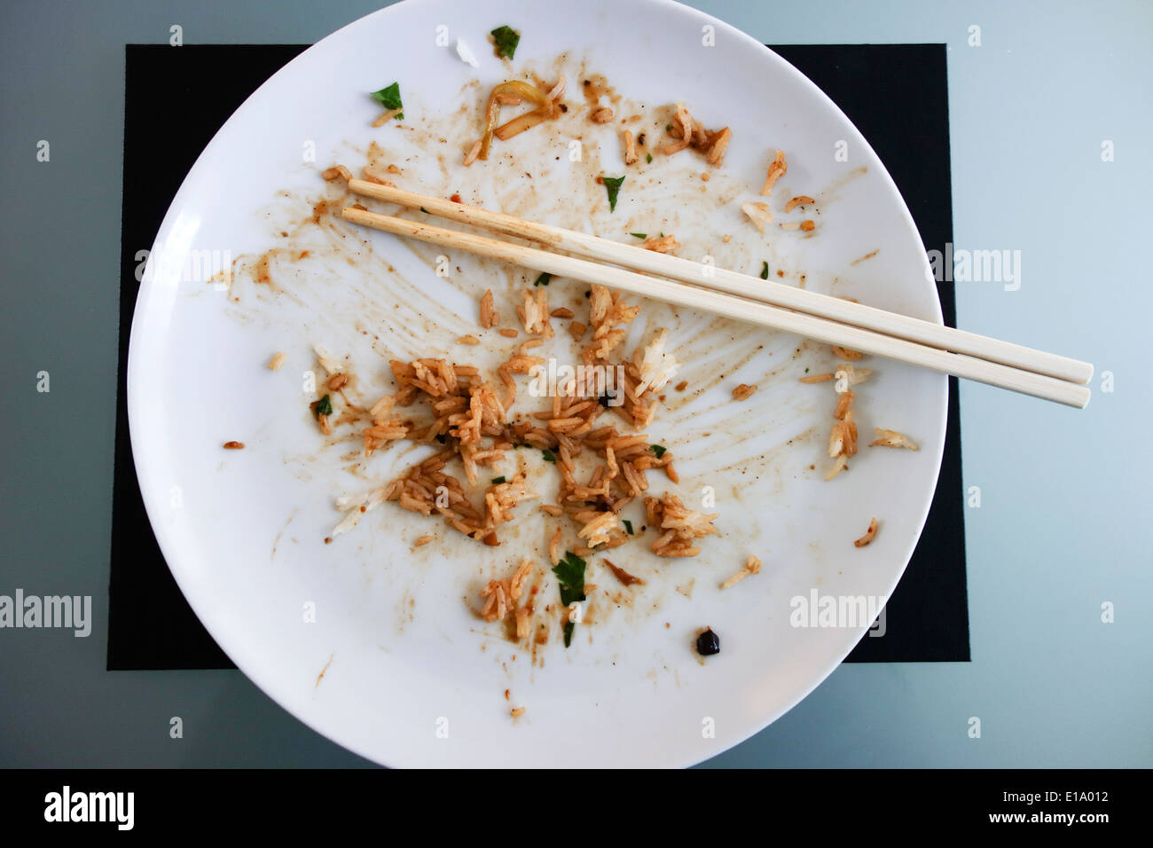 Piastra con residui di cibo su di essa da un pasto insieme con un paio di bacchette Foto Stock