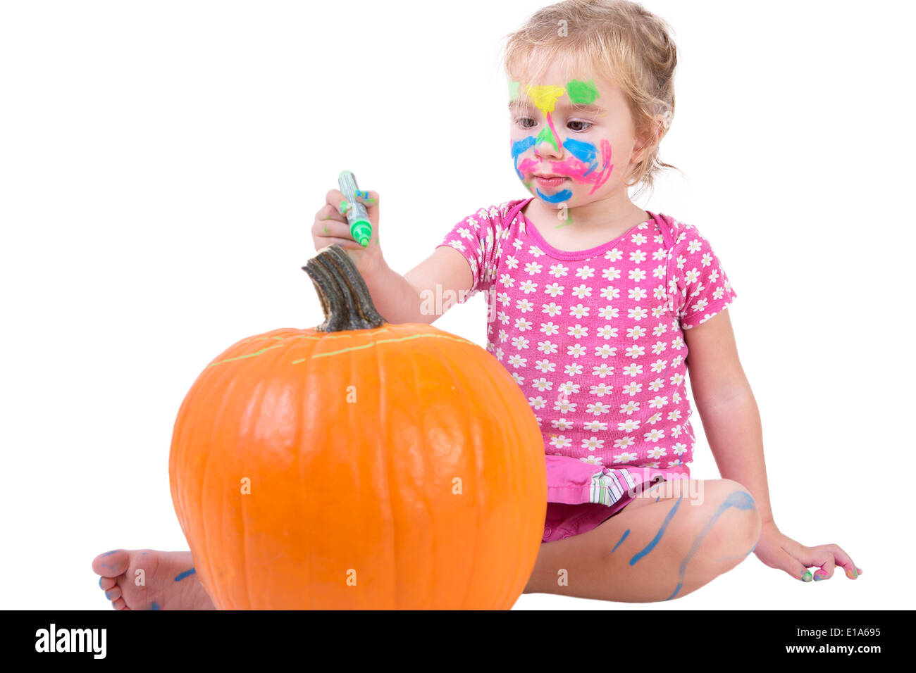 Bella ragazza toddler dipinto il grande arancione zucca di Halloween Foto Stock