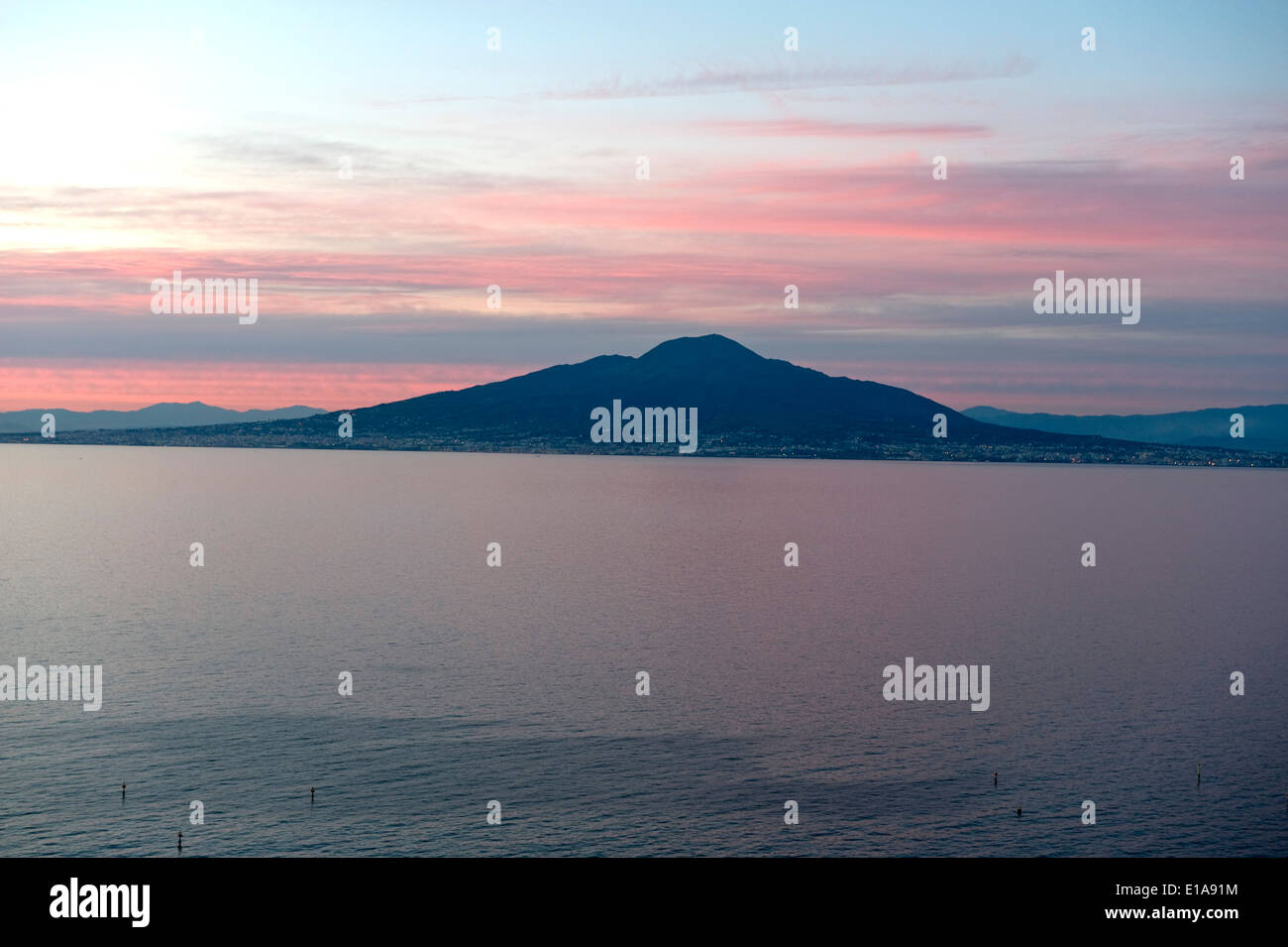 Cielo rosso dietro il Monte Vesuvio, un vulcano attivo, in vista di tutta la baia di Napoli da Sorrento al tramonto Foto Stock