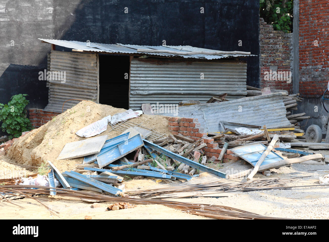 Materiale di costruzione e di detriti in corrispondenza di un sito di costruzione. Telai metallici, acciaio rebar aste, sabbia, terra, tronchi di legno, un foglio di stagno hut Foto Stock