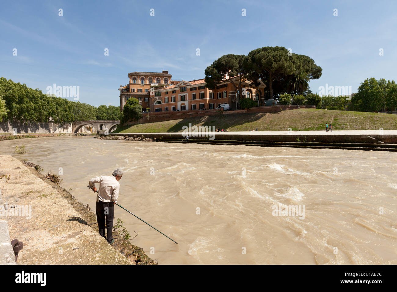 Un uomo locale la pesca nel fiume Tevere , Isola Tiberina in background, Roma Italia Europa Foto Stock