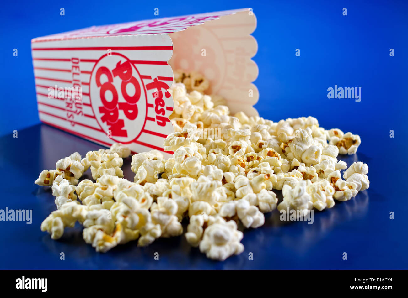Appena scoppiato il popcorn contro un vivido sfondo blu. Foto Stock