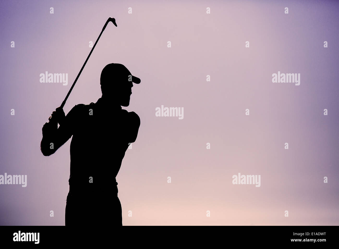 Il Golfer oscillazione un Golf Club stagliano contro un chiaro Cielo di tramonto Foto Stock