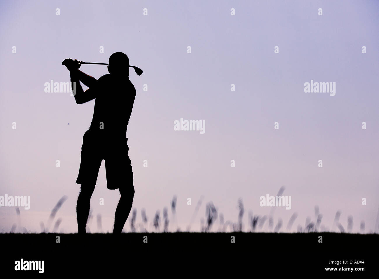 Silhouette di golfista swinging contro chiaro Cielo di tramonto Foto Stock