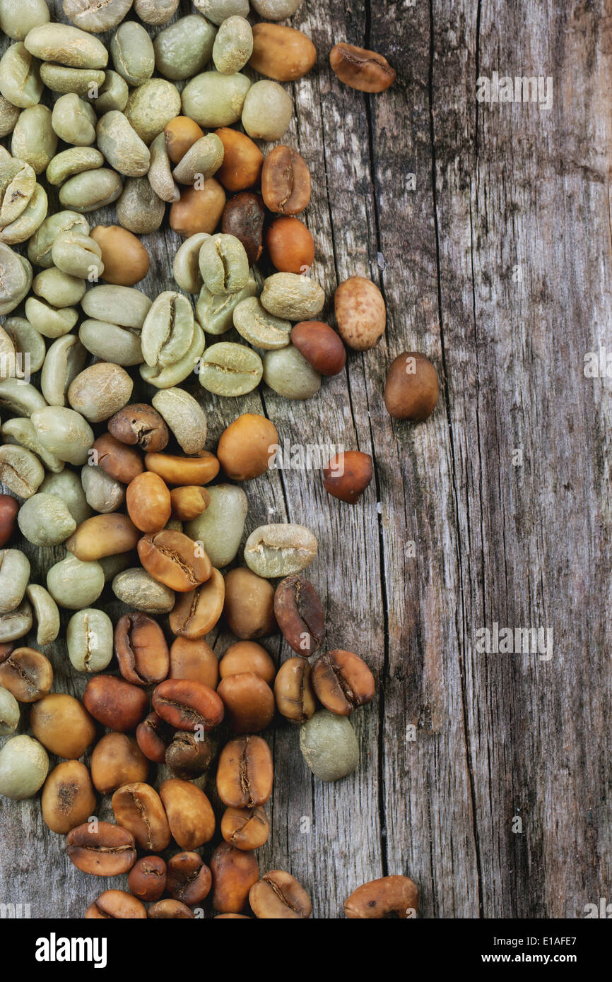 Verde e marrone caffè decaffeinato caffè non torrefatto fagioli su sfondo di legno. Foto Stock