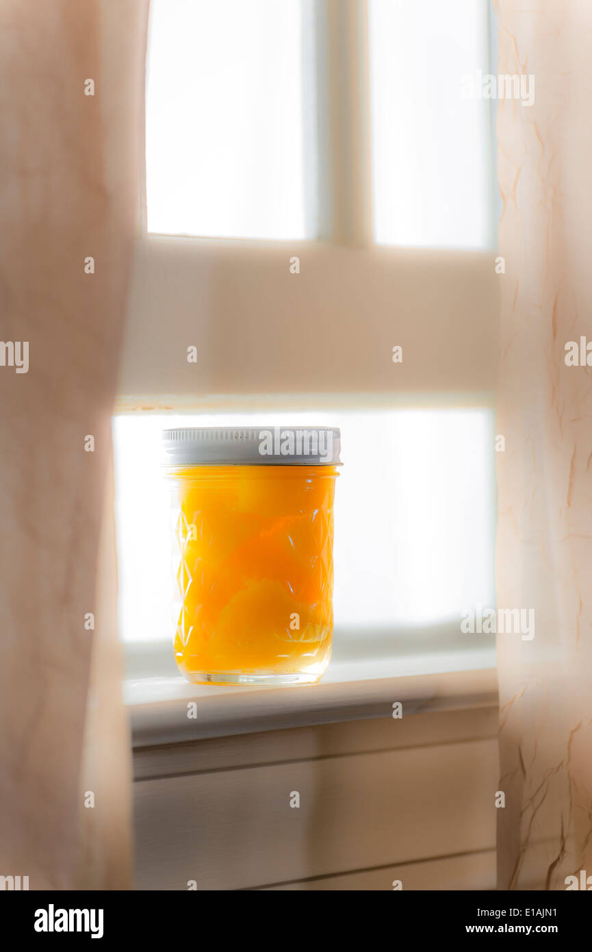 Vasetto di pesche dalla finestra soleggiata con tende giorno di estate Foto Stock