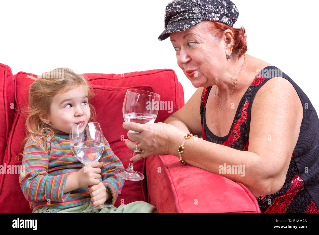 Birichino nonna alla moda e il suo splendido piccolo nipote tostare ogni altra con wineglasses di acqua raffreddata a t Foto Stock