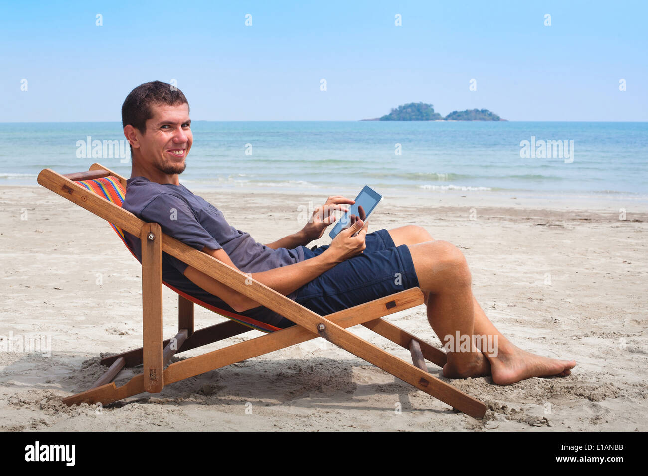 Online banking, ritratto di felice uomo d affari con la compressa sulla spiaggia Foto Stock