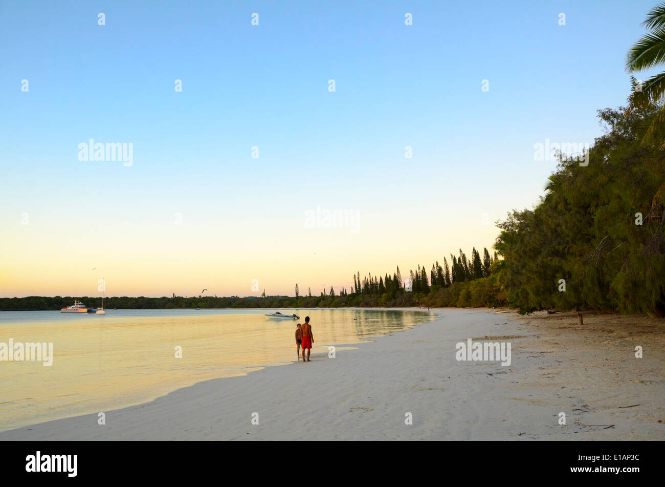 Uomo e ragazzo stand su un vuoto spiaggia tropicale in prima serata, appena prima del tramonto. Foto Stock