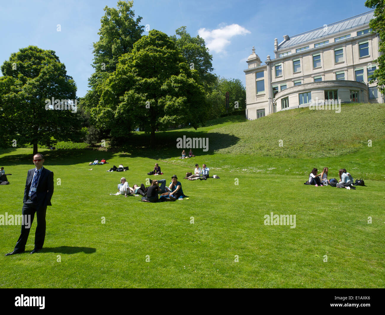 Persone relax nel Parco Leopold in una bella giornata di sole a Bruxelles in Belgio uomo in tuta in piedi Foto Stock