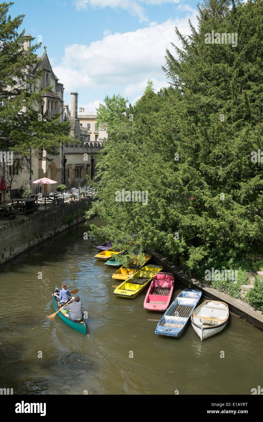 Inghilterra, Oxford. Un uomo e una donna passato canoe ormeggiate imbarcazioni a remi sul fiume Cherwell, Oxford, Regno Unito Foto Stock