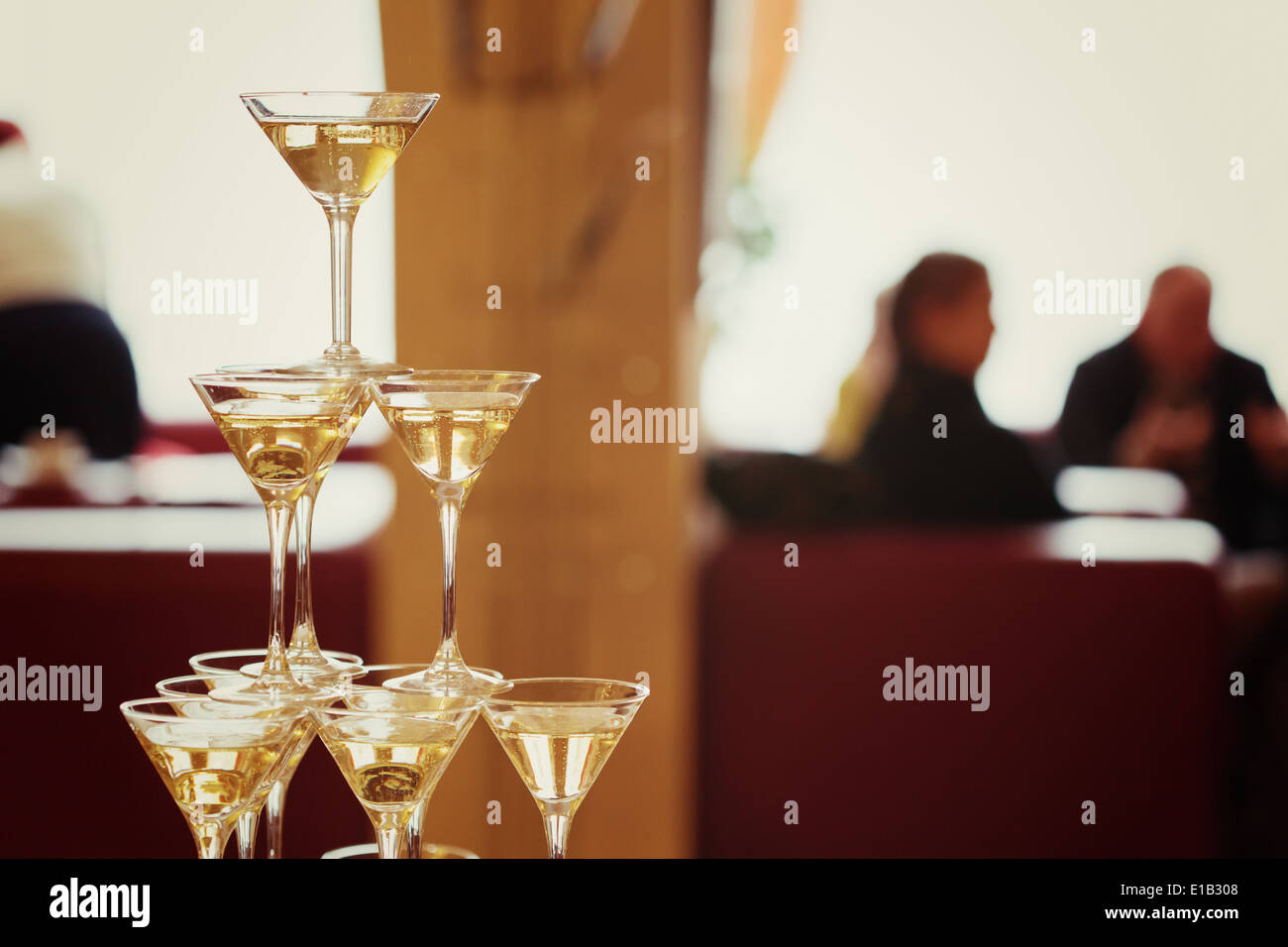 Celebrazione. Piramide di bicchieri di champagne. Dai toni delicatamente. Sagome di persone sullo sfondo. Foto Stock