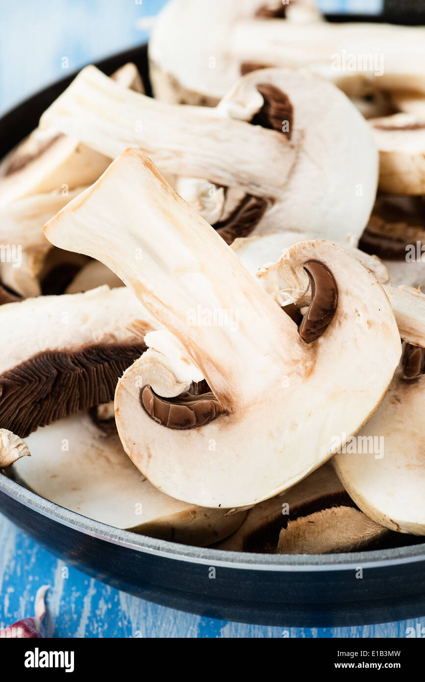 Fresco affettato funghi prataioli nella padella, closeup, il fuoco selettivo Foto Stock