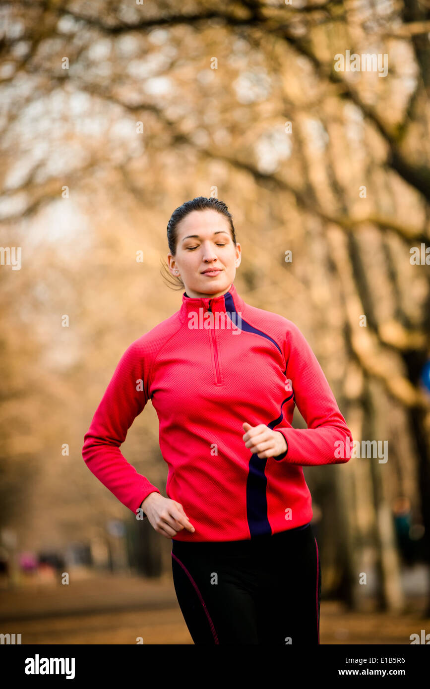 Giovane donna jogging nella struttura ad albero alley - tardo autunno Foto Stock