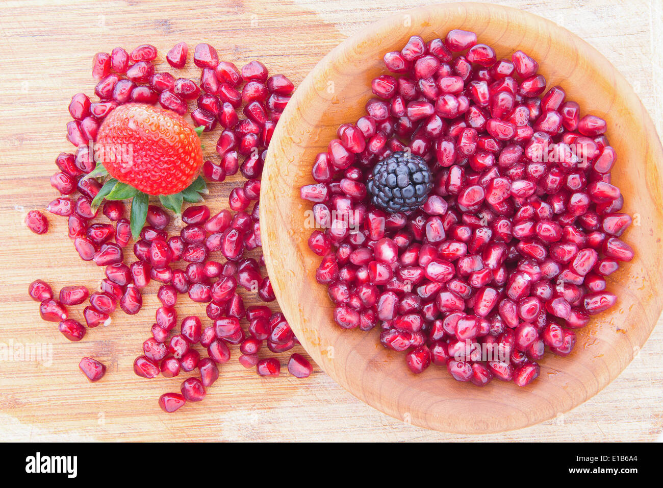 Fresche e mature rosso sugoso i semi di melograno è ricco in vitamina k e utilizzato in extensuly Ayuverda medicina con un singolo fragola Foto Stock