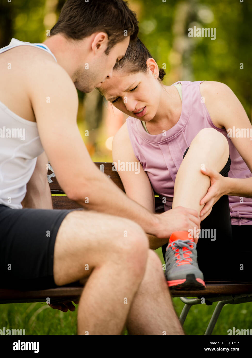 L'uomo contribuisce alla donna che ha ferito la sua gamba quando jogging Foto Stock
