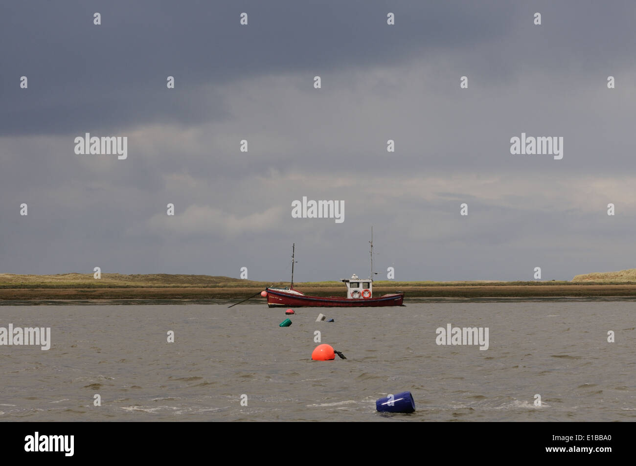 Una barca da pesca ormeggiato Blakeny su un giorno tempestoso con punto Blakeny in background. Blakeney, Norfolk. Regno Unito. Foto Stock