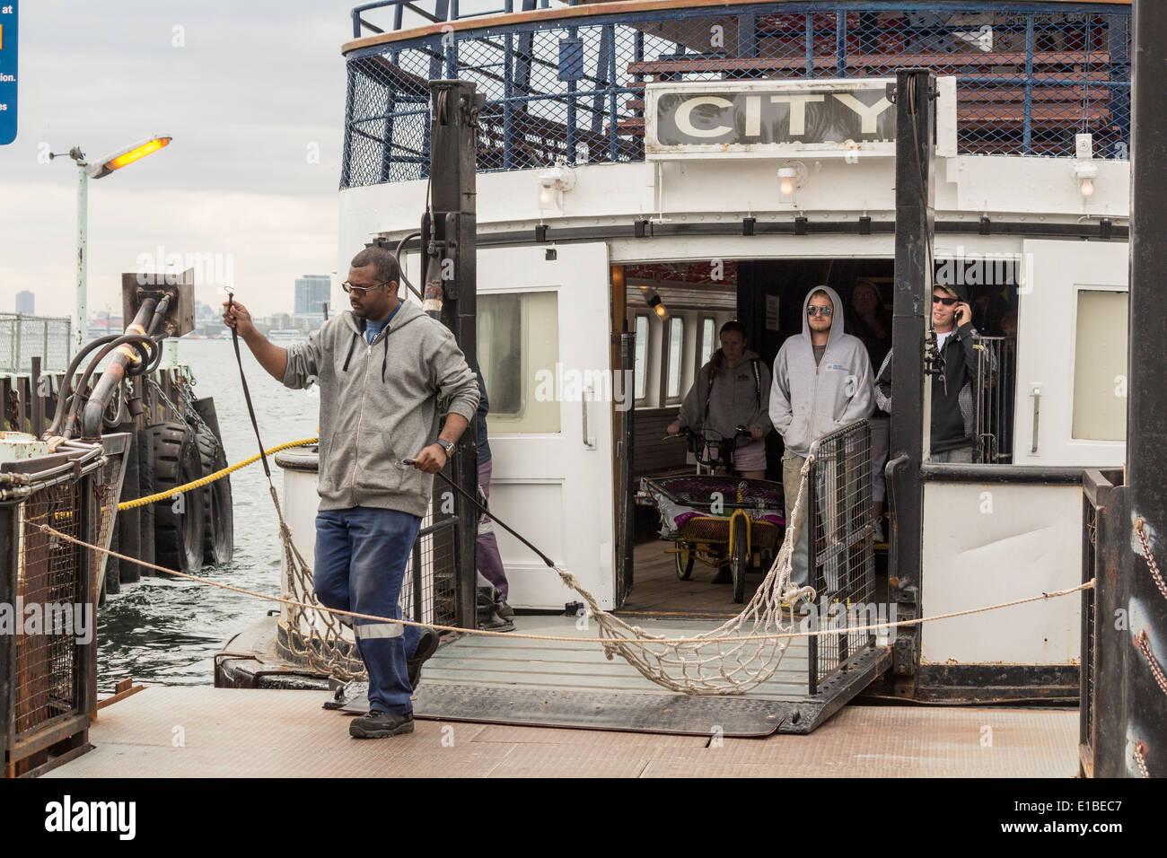 African American maschio lavoratore traghetto si prepara a legare il traghetto per il dock come passeggeri attendere per sbarcare il traghetto al Ward's Island Foto Stock