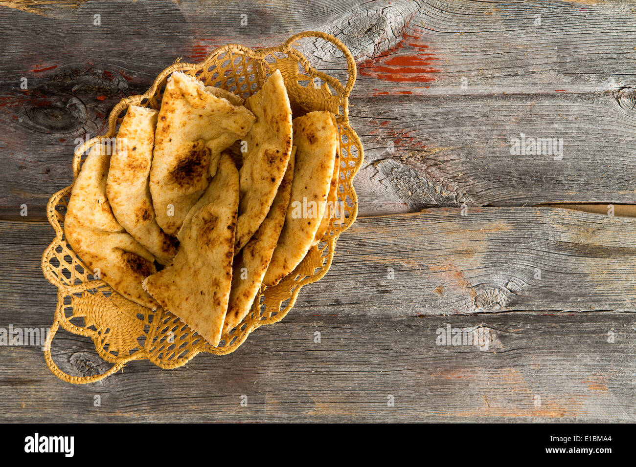 Deliziosi crostini di grano intero pane naan flatbread fette, un pane lievitato cotto in un tandoor forno di argilla, servita in un cesto di vimini Foto Stock