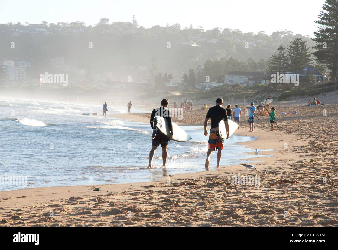 Due surfisti che trasportano le tavole da surf camminando lungo la spiaggia. Foto Stock