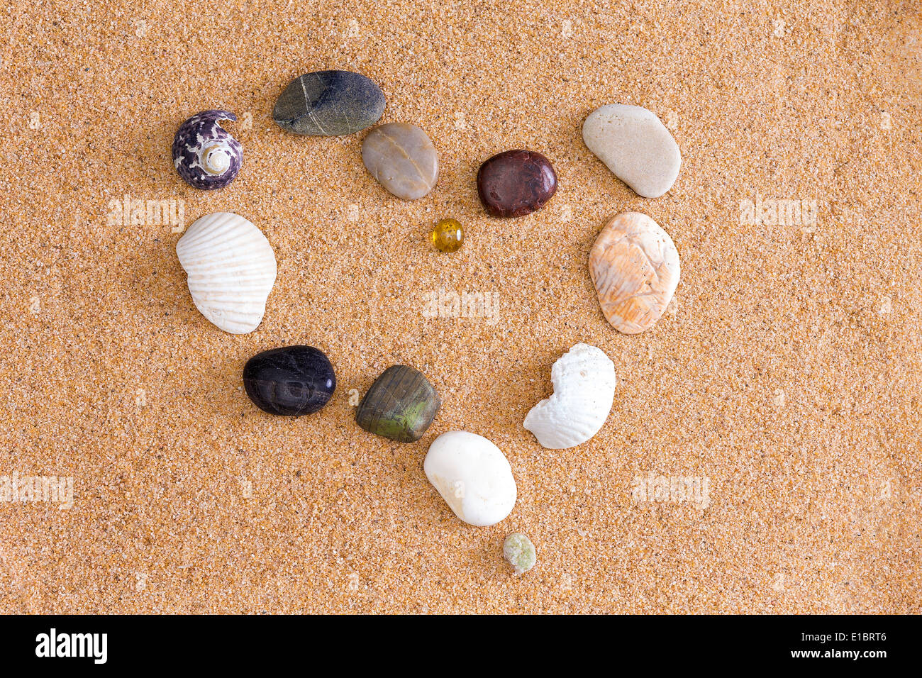 Romantico cuore al mare sulla spiaggia dorata sabbia formata da rocce e rotture di gusci raffigurante un San Valentino o anniversario w Foto Stock