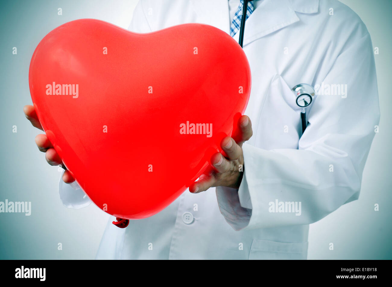 Un medico in possesso di un cuore rosso a forma di palloncino, che simboleggia la medicina cardiovascolare Foto Stock