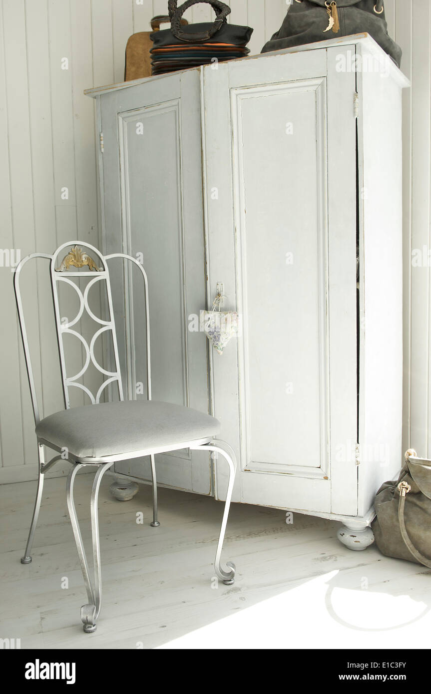 Vecchia credenza bianco e bianco in ferro battuto sedia sul pavimento in legno Foto Stock