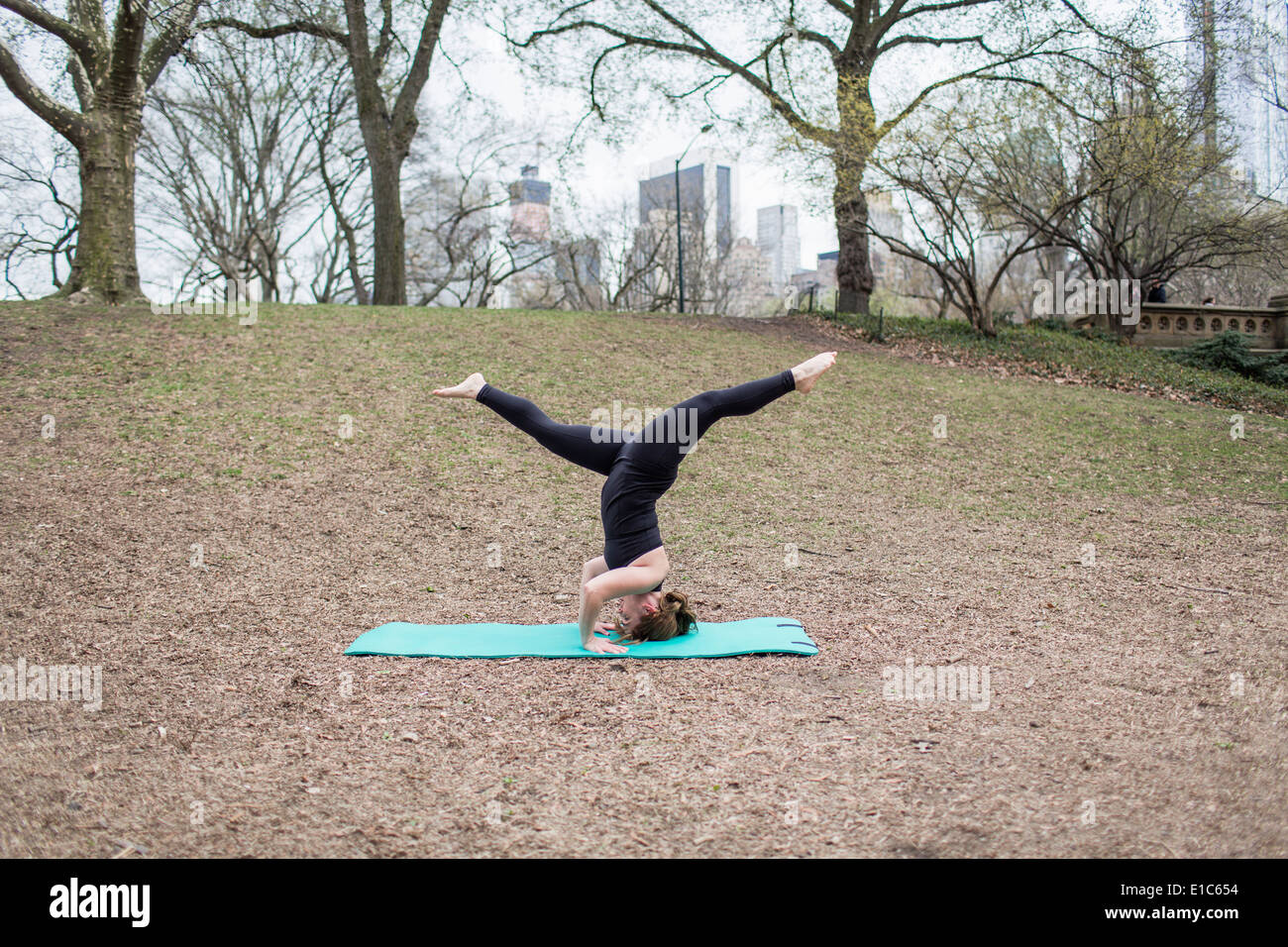 Una giovane donna in Central Park, in un nero leotard e gambali, fare yoga. Foto Stock