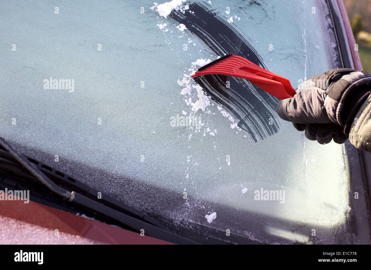 La raschiatura del ghiaccio dal finestrino dell'auto, con copia spazio sulla sinistra Foto Stock