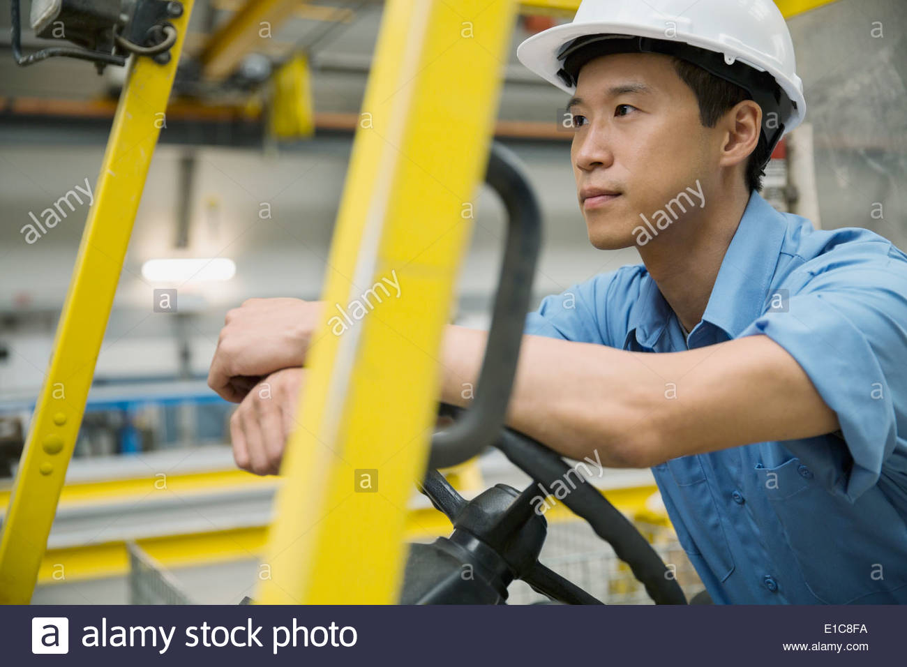 Malinconici lavoratore operante il carrello elevatore in fabbrica Foto Stock