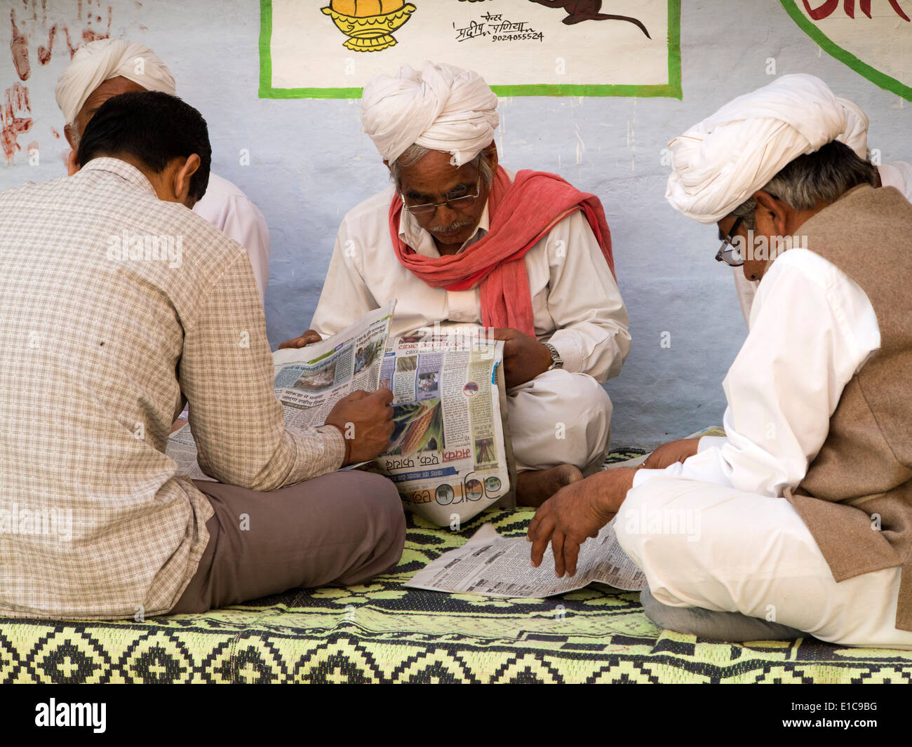 India Rajasthan, Jaisalmer, uomini anziani sat leggere Hindi lnguage quotidiani in ombra Foto Stock