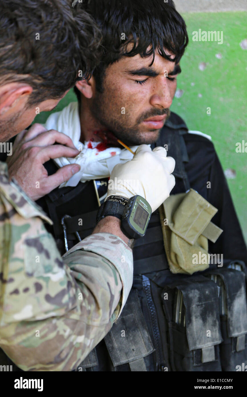 Un esercito usa le forze speciali medic considera un esercito nazionale afghano forza speciale commando ferito durante un firefight con i Talebani ribelli 27 maggio 2014 nel quartiere Nejrab, provincia di Kapisa, Afghanistan. Foto Stock
