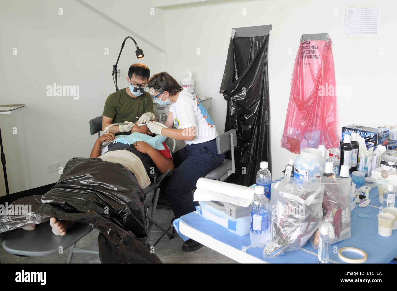 Esercito canadese Capt. Jason Yee e U.S. Navy Corpsman ospedale di terza classe Angelo Herndon fornisce il trattamento dentale per una donna duri Foto Stock