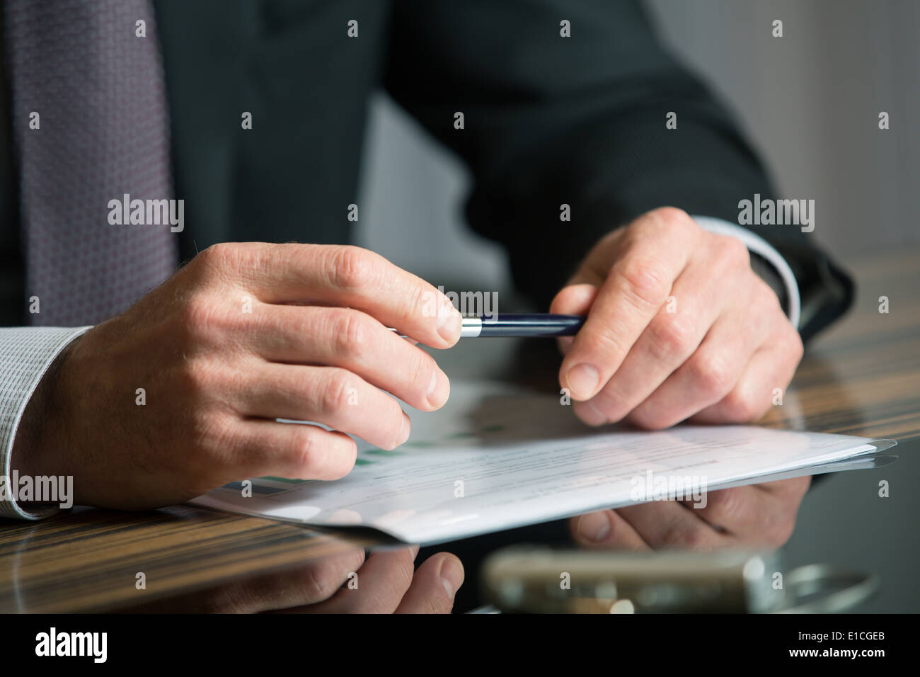 Uomo con le mani in mano in possesso di una penna nera in entrambe le braccia in un gesto di pensiero durante una riunione o negoziazione Foto Stock