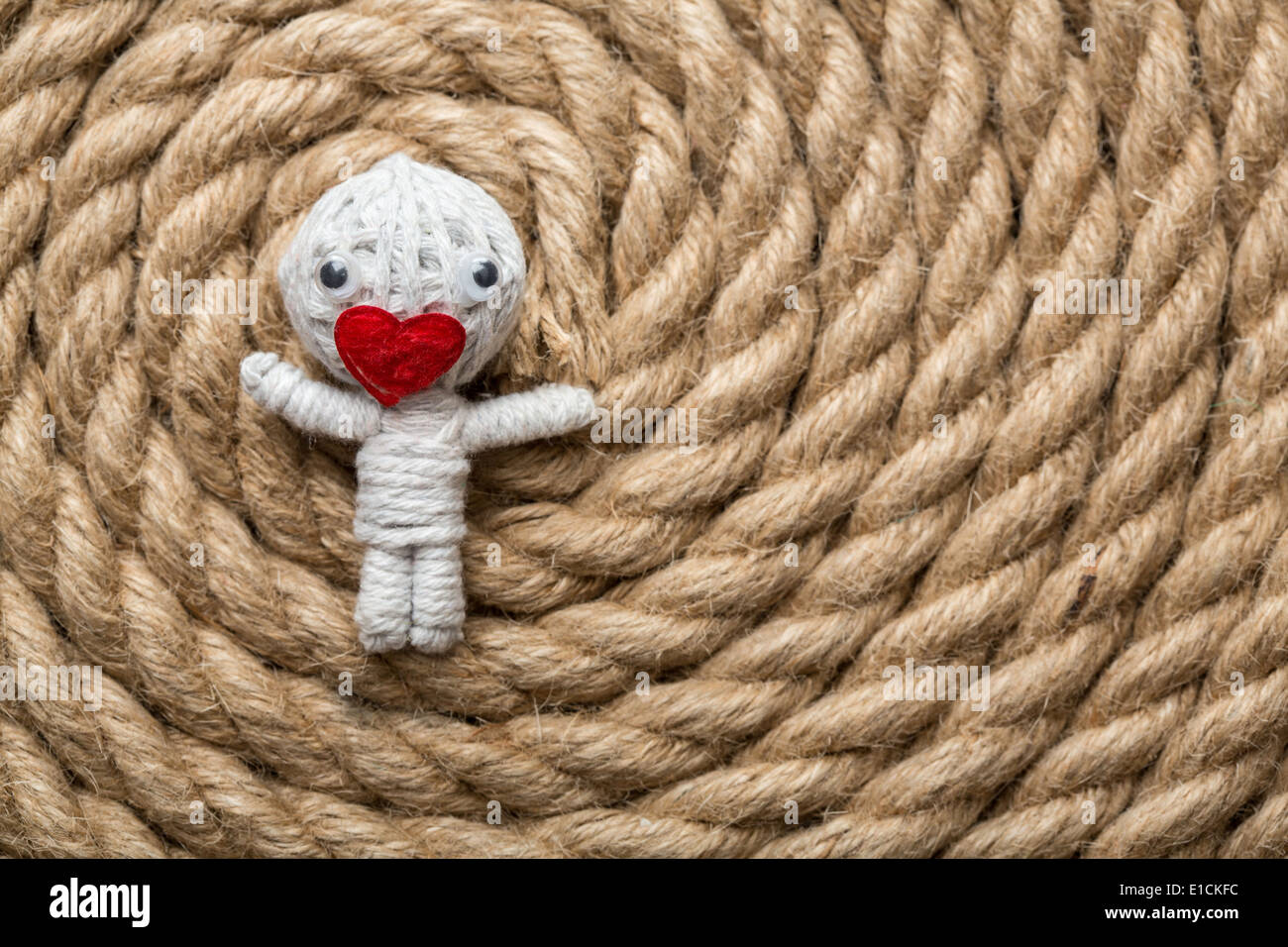 Valentine doll realizzato dal filo bianco con un cuore al posto della bocca , che giace su una corda sullo sfondo Foto Stock