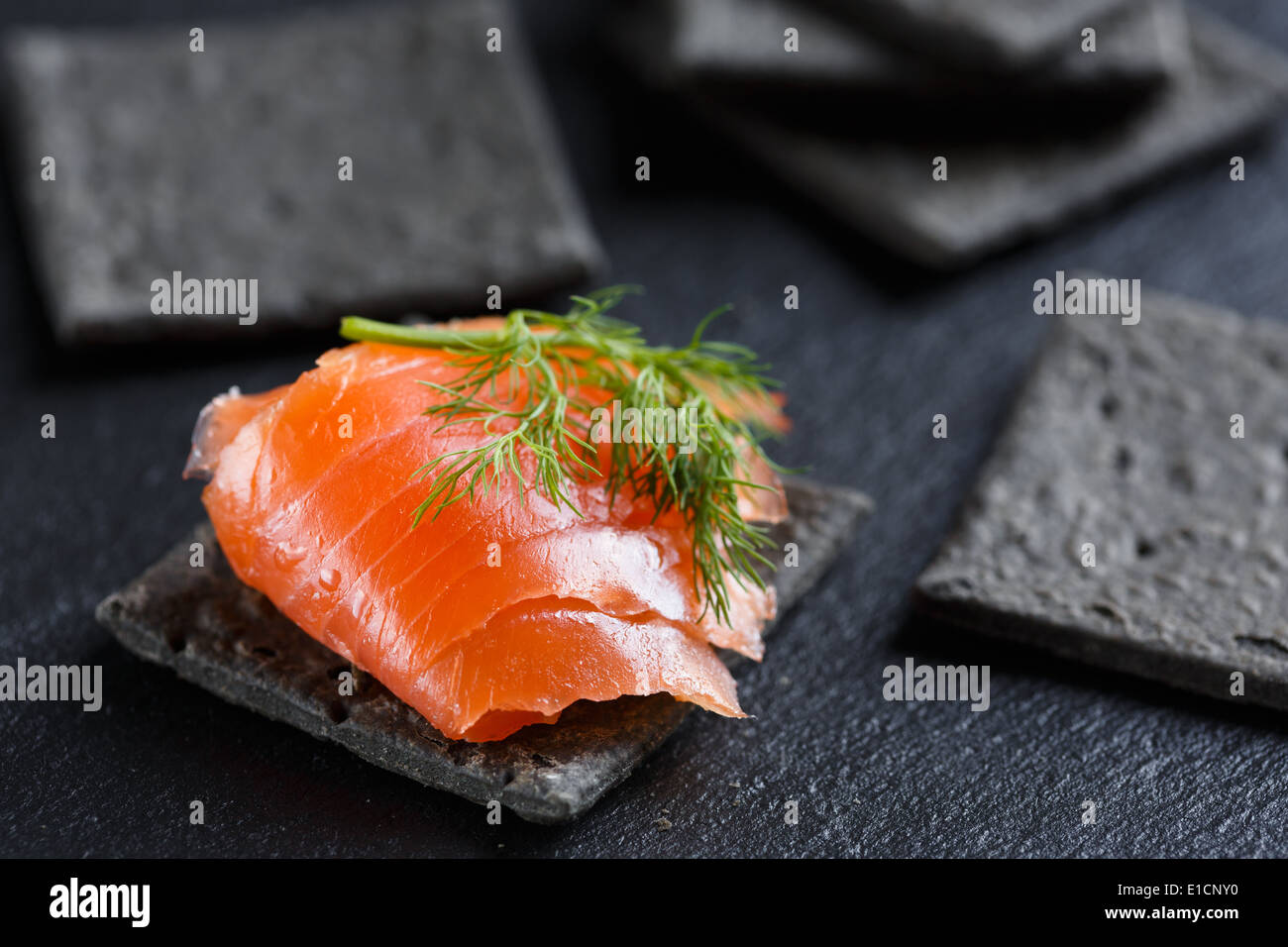 Salmone affumicato su nero cracker Foto Stock