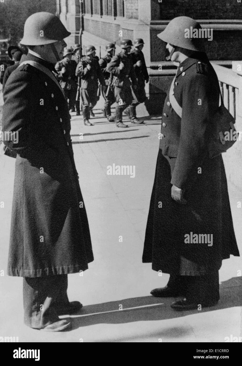 Occupazione nazista della Norvegia durante la guerra mondiale 2. Due poliziotti norvegesi guardando un distaccamento di truppe tedesche marciando attraverso Foto Stock
