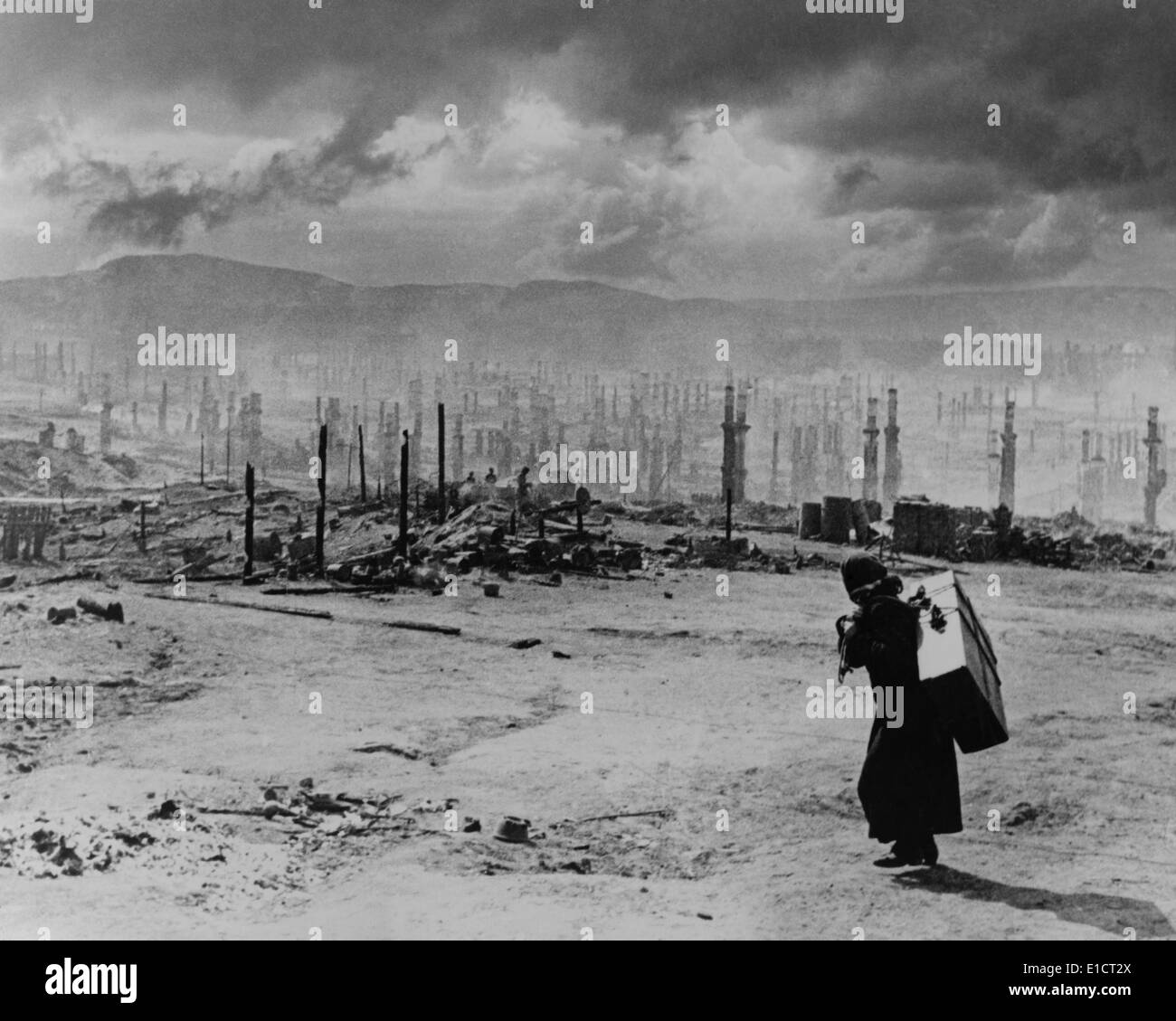 Guerra Mondiale 2, Rovine di Murmansk nel 1942. Donna sovietica portando grande valigia sulla sua schiena, passeggiate oltre i resti carbonizzati della Foto Stock