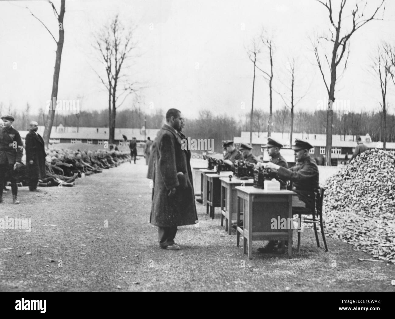 I funzionari della Gestapo la registrazione dei dati sui prigionieri in arrivo al campo di concentramento tedesco. Molti altri sono seduti a terra Foto Stock