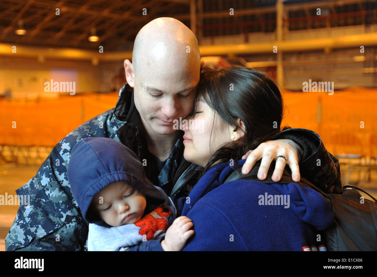 Stati Uniti Navy Master-at-Arms di terza classe Michael Cassano, sinistra, abbraccia la moglie e il bambino prima che a bordo di un aeromobile durante una Foto Stock