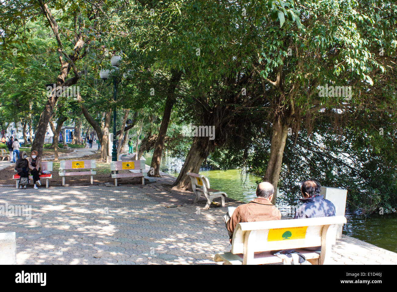 Residenti vietnamiti rilassante accanto al lago Hoan Kiem ad Hanoi, Vietnam. Il lago è la città del centro culturale e storico. Foto Stock