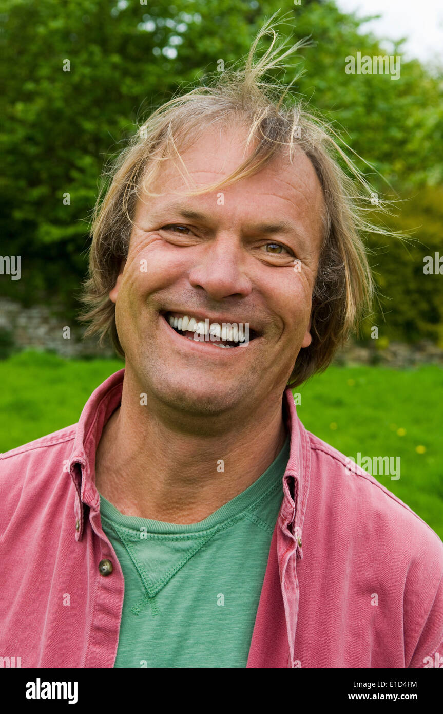 Un uomo in abiti casual con capelli biondi, sorridente largamente. Foto Stock