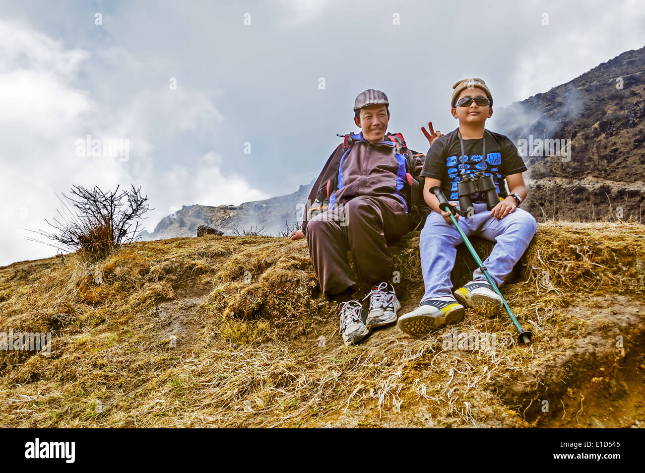Due escursionisti tenendo il resto e mostrando segno di vittoria sul percorso di trekking a Sandakphu in Himalaya Foto Stock