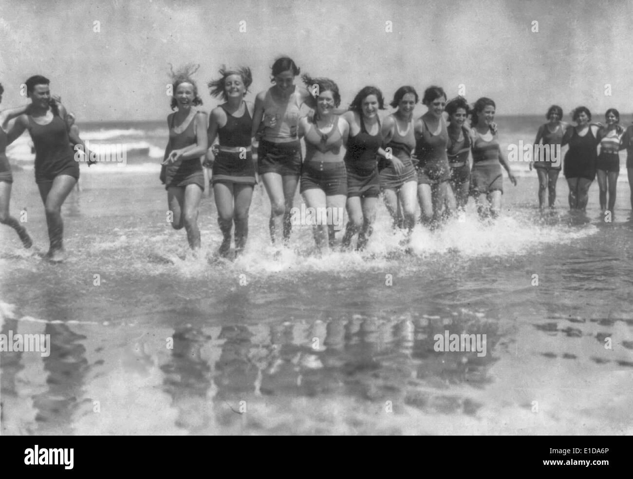 Nel surf, Wildwood Ville, Wildwood, NJ, circa 1920 - gruppo di giovani donne in costume da esecuzione di spalla a spalla attraverso l'acqua lungo la spiaggia Foto Stock