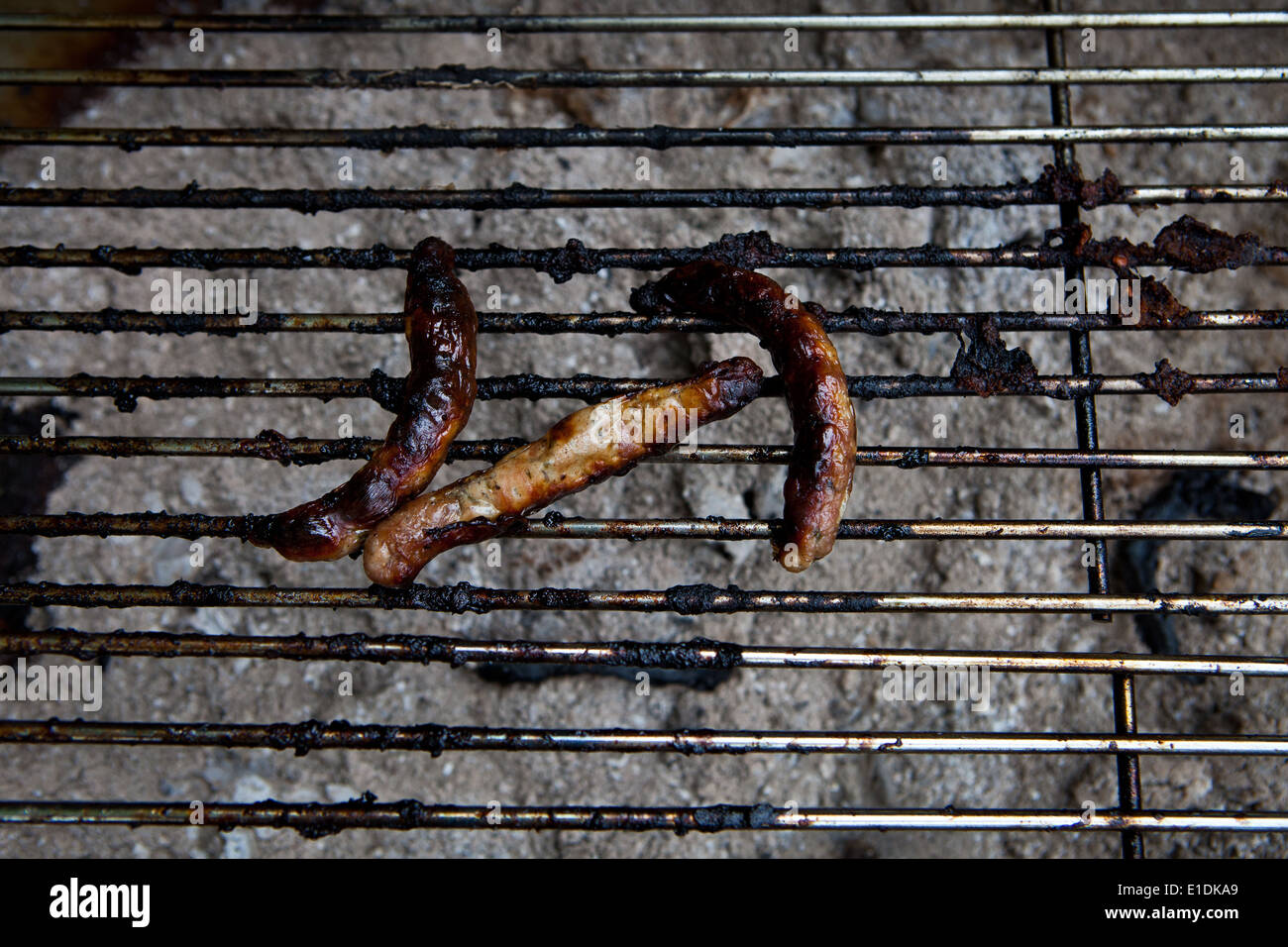 Tre bruciato salsicce sulla griglia per il barbecue Foto Stock