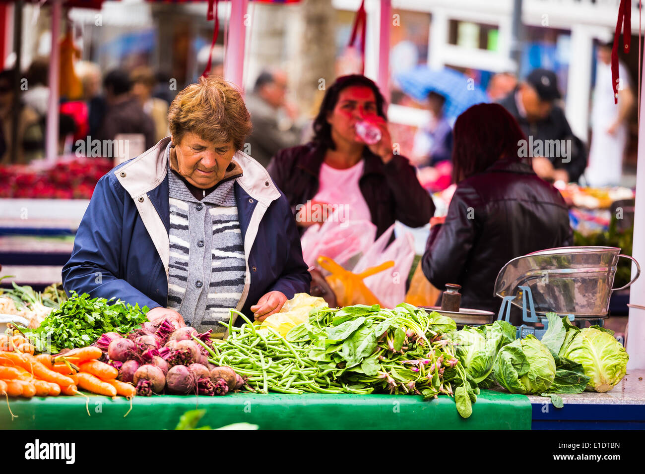 Una donna che vende le verdure fresche dal suo stallo a il mercato giornaliero in Split Croazia Foto Stock