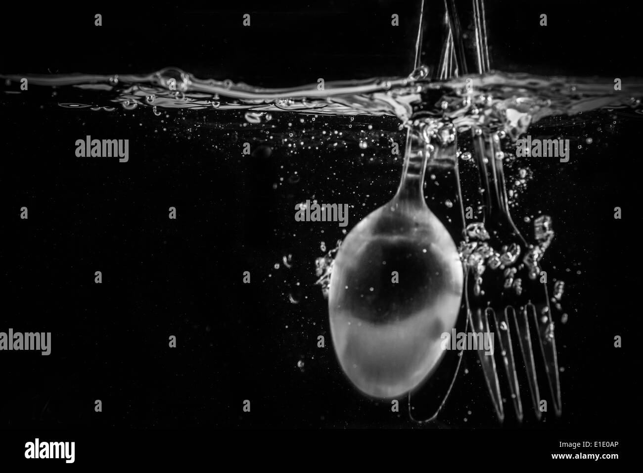 Un cucchiaio e forchetta cade in una vasca di acqua Foto Stock